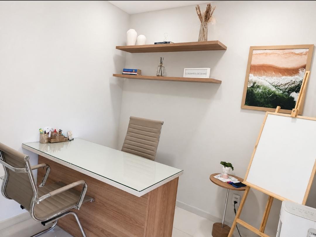 Mesa de atendimento com prateleiras de madeira, um quadro do mar e um cavalete com tela em branco